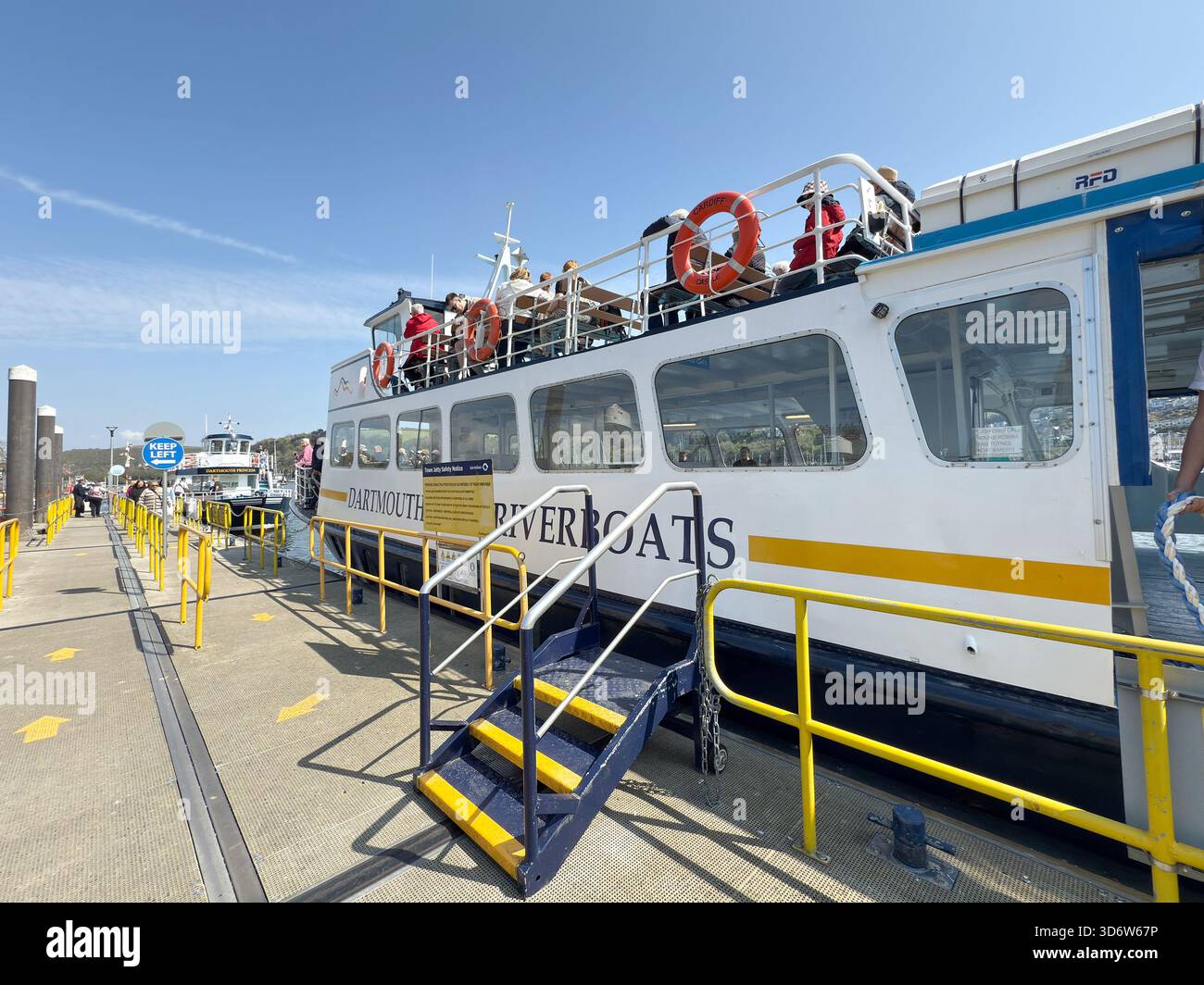 Dartmouth, Devon, Inghilterra, Regno Unito - 24 aprile 2025: Persone sedute sul ponte superiore di una nave da crociera turistica sul fiume presso il molo di Dartmouth - Immagine stock catturata con smartphone