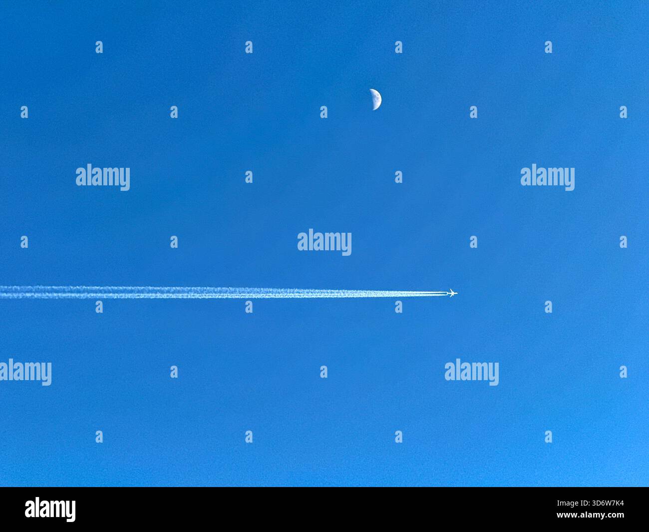 Jet per le vacanze in volo con contrafforti che passano la luna su un cielo blu profondo - Immagine stock catturata con smartphone