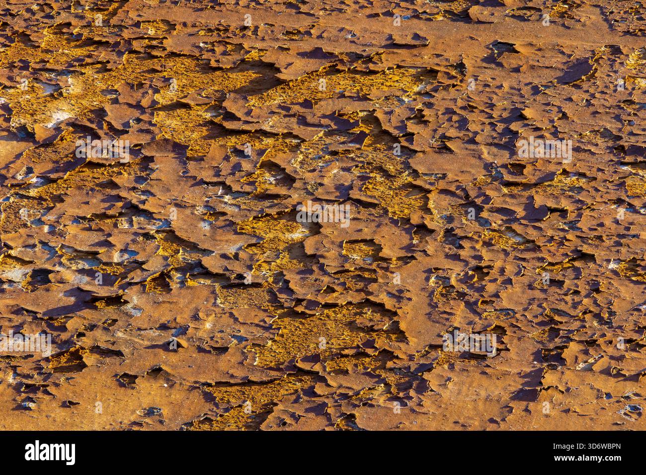 Primo piano di ruggine resistente agli agenti atmosferici con strati di pelatura e patina arancione calda, sfondo industriale dettagliato. Foto Stock