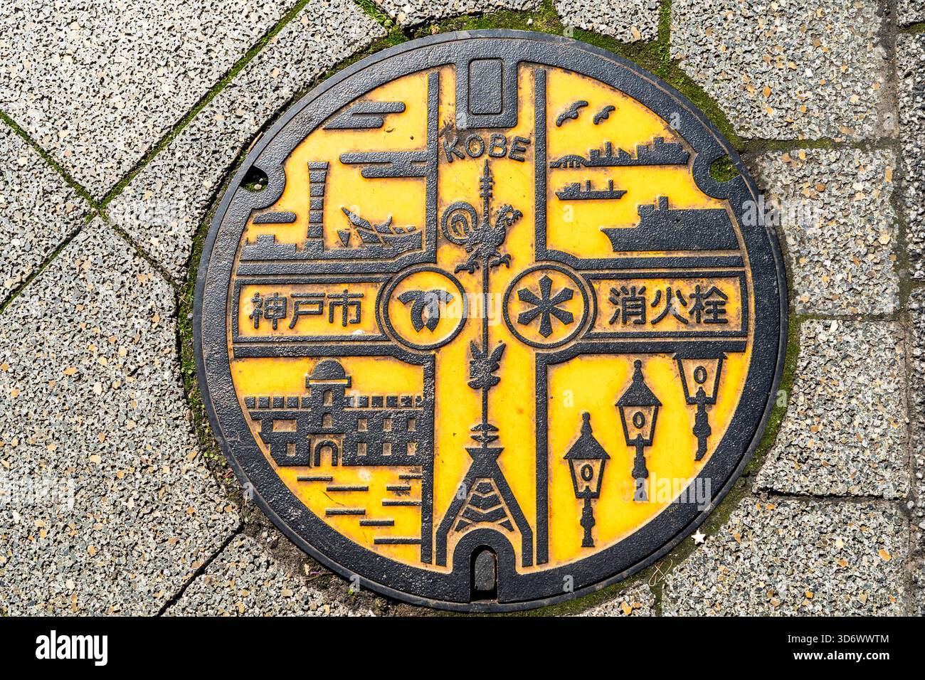 Tombini decorati in giallo e nero con varie navi iconiche, edifici come la Torre del Porto e simboli della città di Kobe. Foto Stock