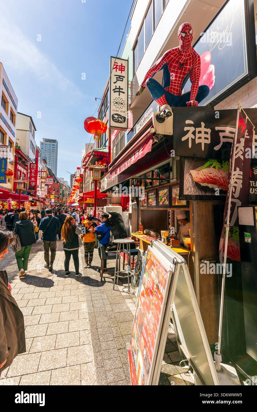 Vista lungo la strada principale di Chinatown, piena di turisti che passeggiano lungo il sole, passano i ristoranti e i negozi su entrambi i lati. Foto Stock