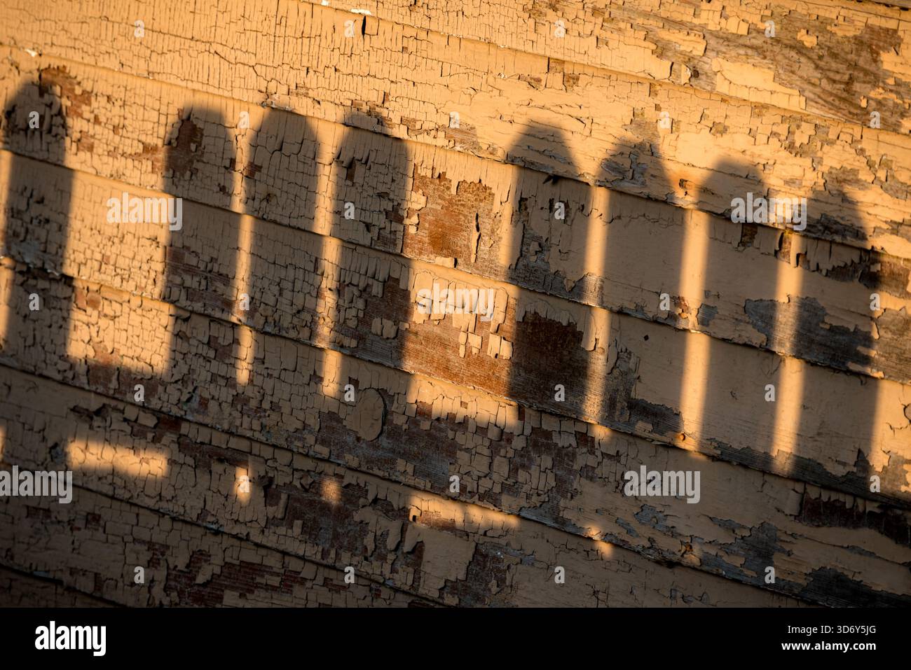 L'ombra di una recinzione sul muro di una vecchia casa è Anatone, Washington, USA. Foto Stock