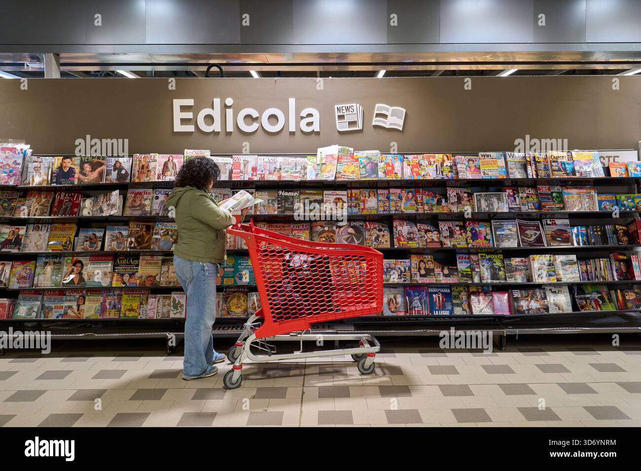 Woman Browsing Magazine e Quotidiani presso l'edicola del supermercato Foto Stock