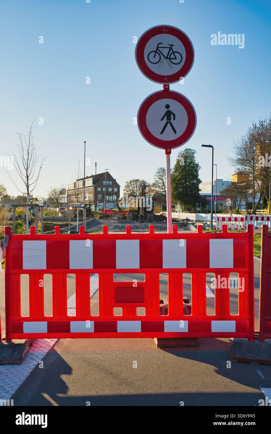 Barriere e segnali stradali segnalano una strada chiusa a Neuss, Germania. L'area è in fase di costruzione e il cielo azzurro illumina la scena. A piedi Foto Stock