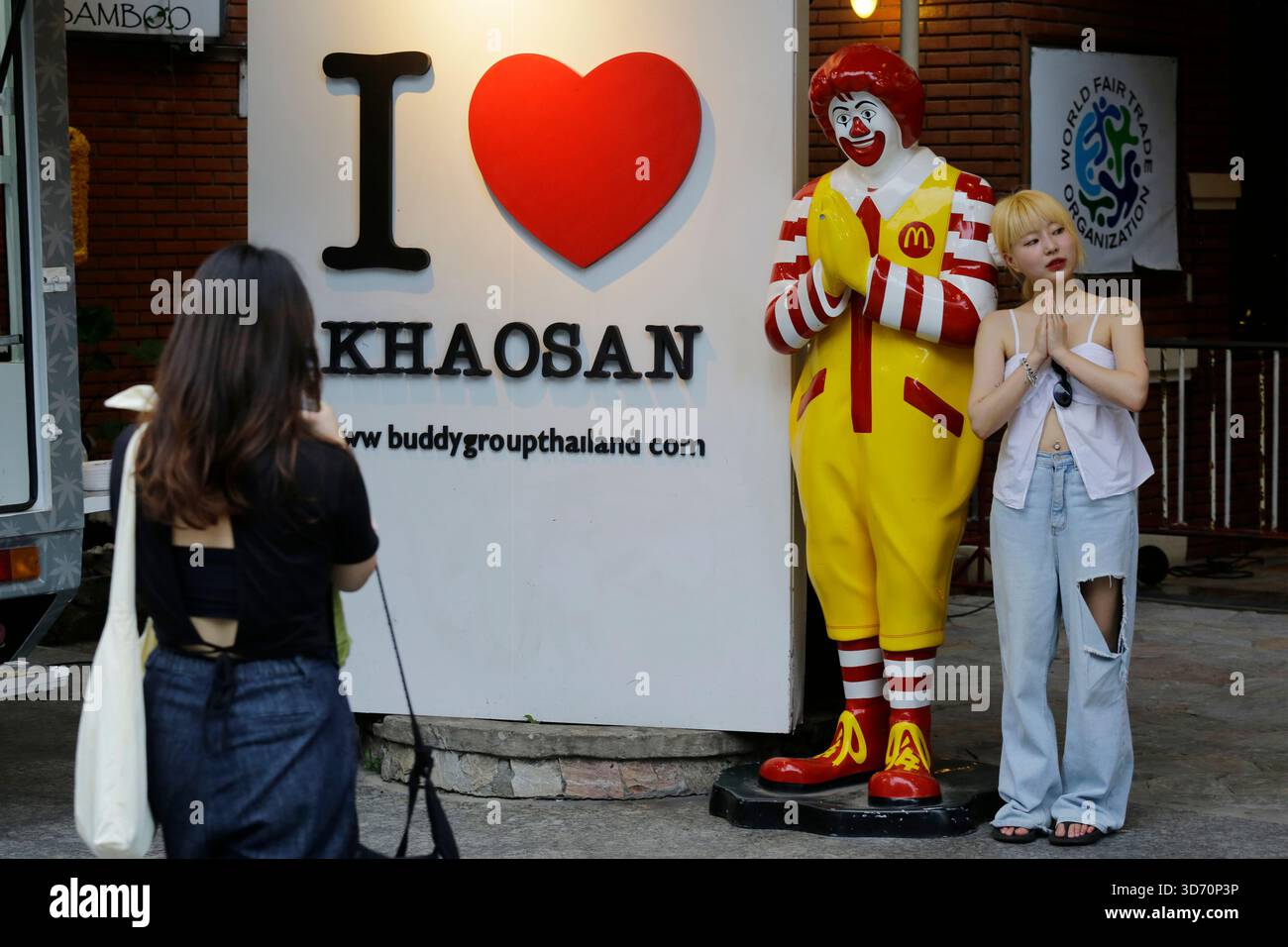 Bangkok, Thailandia - 22 luglio 2022: I turisti posano per le foto accanto a un manichino Ronald McDonald che gestiva un Wai, o Namaste, al McDonald's.. Foto Stock