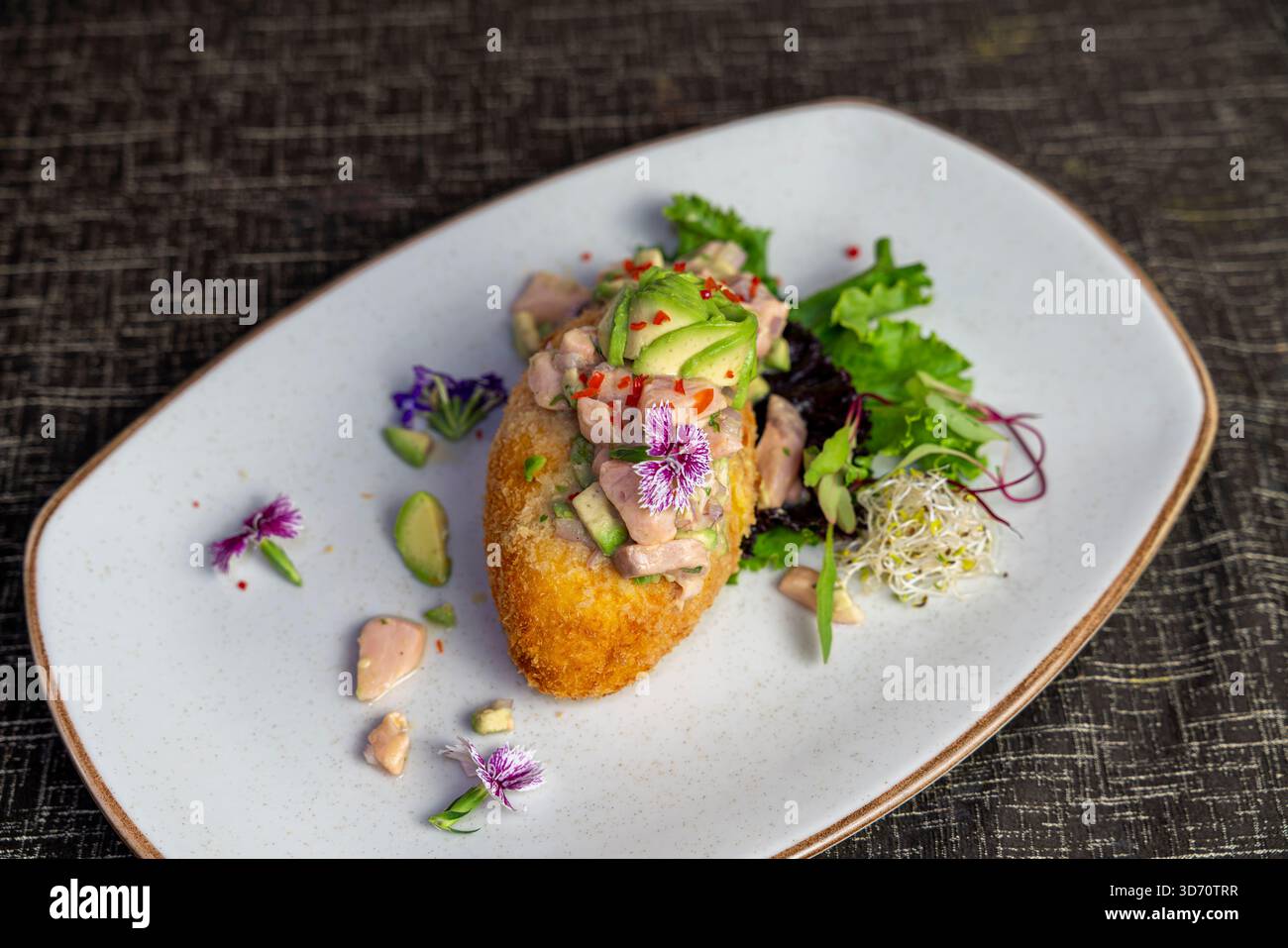 Croquette gourmet condita con pollo e avocado, placcatura artistica con fiori commestibili, presentazione moderna della cucina del ristorante. Foto Stock