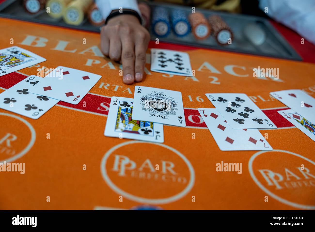 Mano del mazziere che spara carte su un tavolo di blackjack con chip e carte da gioco all'interno di un casinò, concetto di gioco d'azzardo, rischio, strategia, intrattenimento. Foto Stock