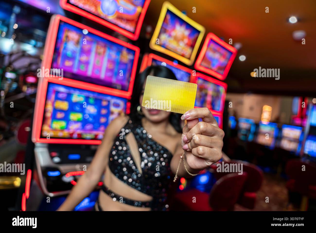 Donna che detiene la tessera del casinò di fronte alle slot machine, concetto di gioco d'azzardo con fedeltà, intrattenimento, gioco, vita notturna e interni di lusso. Foto Stock