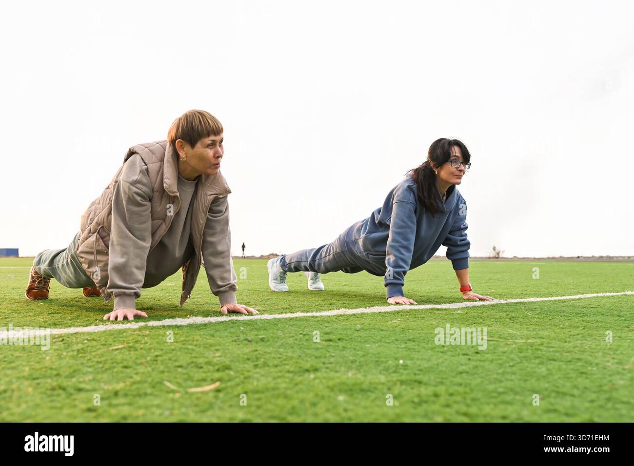 Due donne russe, di 50 e 60 anni, si esibiscono in una classica posa su una tavola in uno stadio. Foto Stock