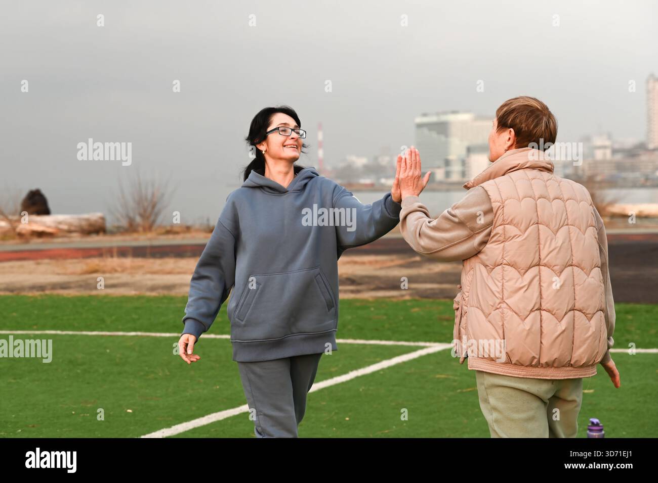 Due amiche russe, di 50 e 60 anni, in tuta, cinque in alto e ridere. Foto Stock