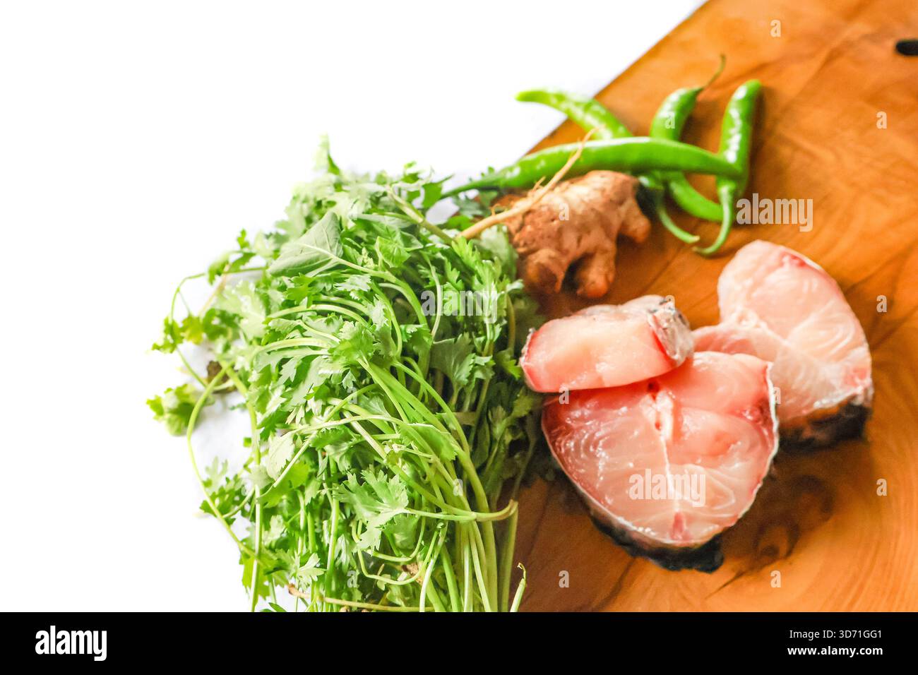 Pesce pronto per cucinare. Pezzetti di pesce fresco su una tavola di legno. Pesce crudo e verdure. Foto Stock