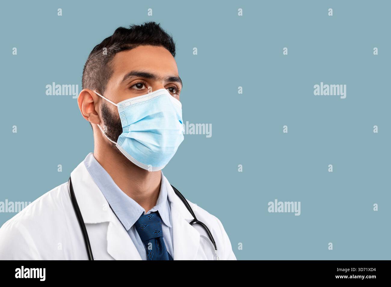 Medico che indossa una maschera e uno stetoscopio in un ambiente clinico durante la crisi sanitaria Foto Stock