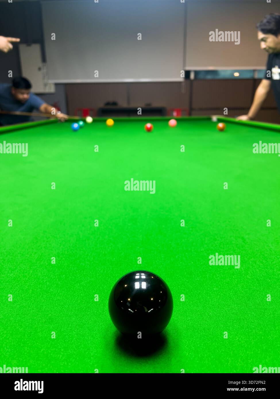 Pekan, Pahang, Malesia - 23 novembre 2025: Un tiro ad angolo basso di una partita di snooker in corso. Una singola palla nera si trova in primo piano Foto Stock
