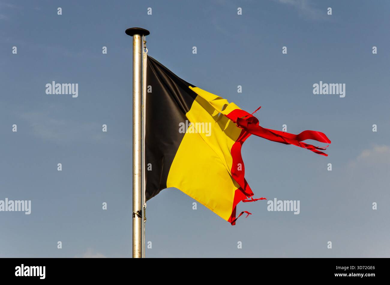 Una bandiera tricolore belga leggermente danneggiata in una giornata di sole Foto Stock