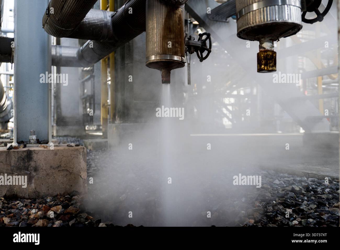 Rilascio controllato di vapore da un sistema di sfiato della pressione industriale, che mostra le tubazioni di sfiato, il flusso di nebbia e le operazioni di sicurezza all'interno di un impianto petrolchimico Foto Stock