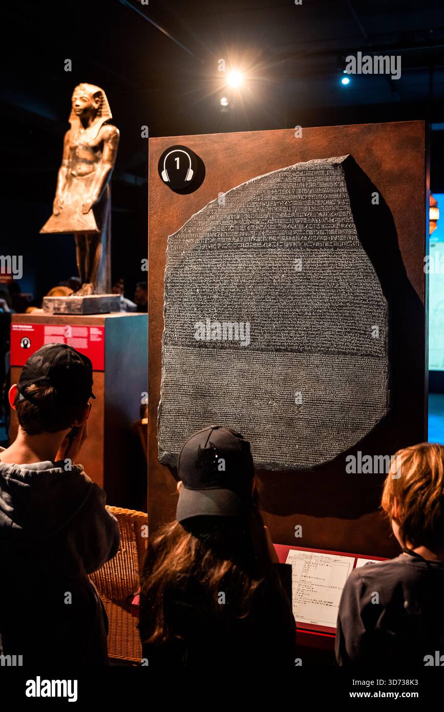 Bratislava, Slovacchia - 15 novembre 2025: I bambini osservano una mostra di pietre di Rosetta durante una mostra Tutankhamon, circondati da manufatti egiziani Foto Stock