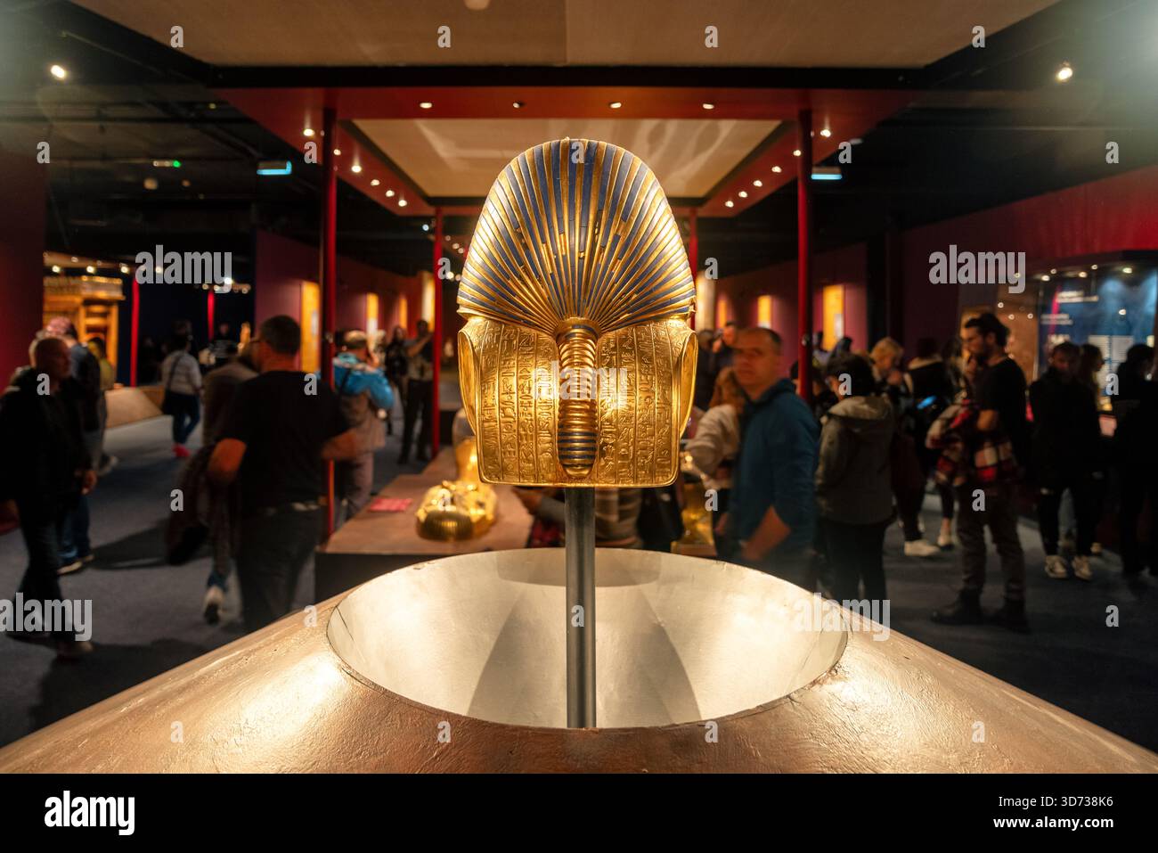 Bratislava, Slovacchia - 15 novembre 2025: I visitatori osservano una maschera funeraria dorata durante una mostra Tutankhamon, circondata da manufatti egiziani Foto Stock