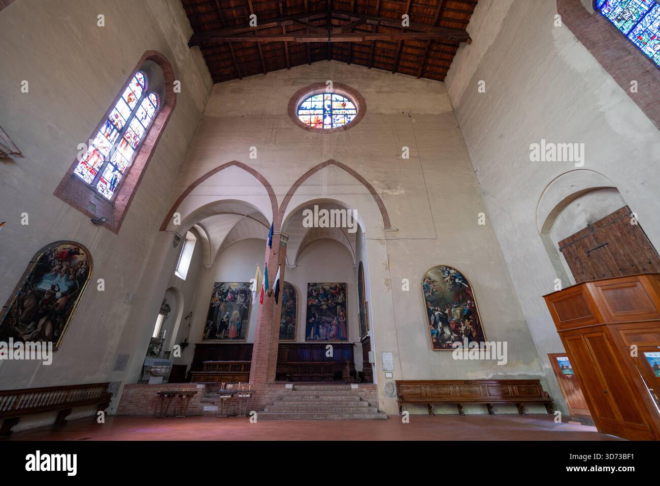 Archi gotici e vetrate colorate illuminano la Basilica Cateriniana San Domenico a Siena. Gli interni austeri presentano affreschi e travi in legno, re Foto Stock