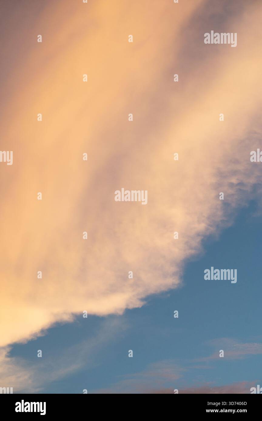 Le morbide nuvole arancioni si estendono attraverso il cielo durante il tramonto, creando una vista mozzafiato mentre il giorno passa alla notte. Foto Stock