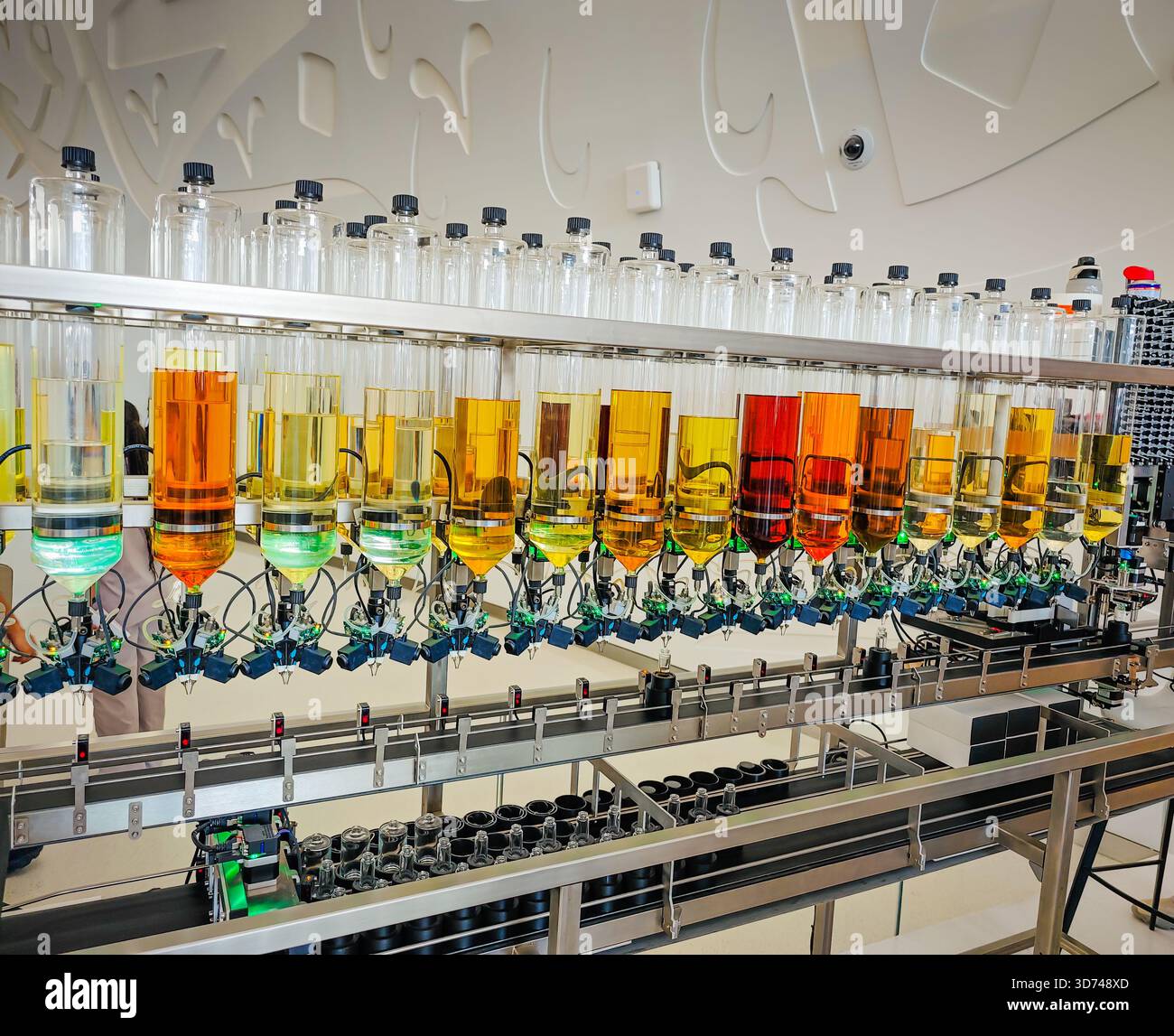 Produzione di profumi. Profumi diversi in bottiglia. Linea di produzione robotizzata di profumi con erogazione automatica di fragranze Foto Stock