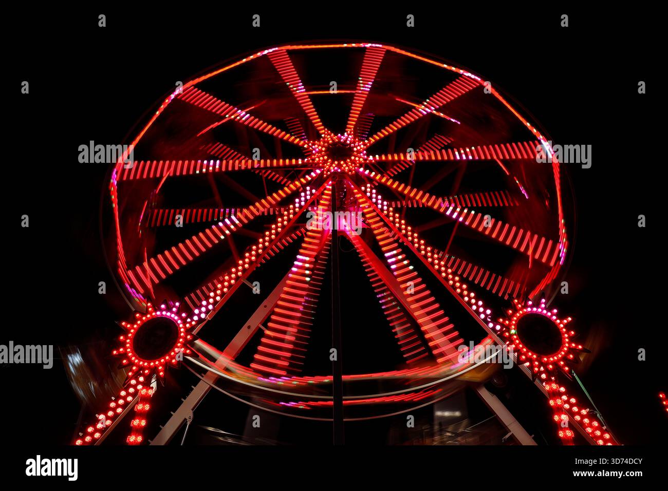 Lunga esposizione di una ruota panoramica illuminata di notte durante l'evento dell'aurora boreale al Temple Newsam di Leeds, West Yorkshire, Regno Unito Foto Stock