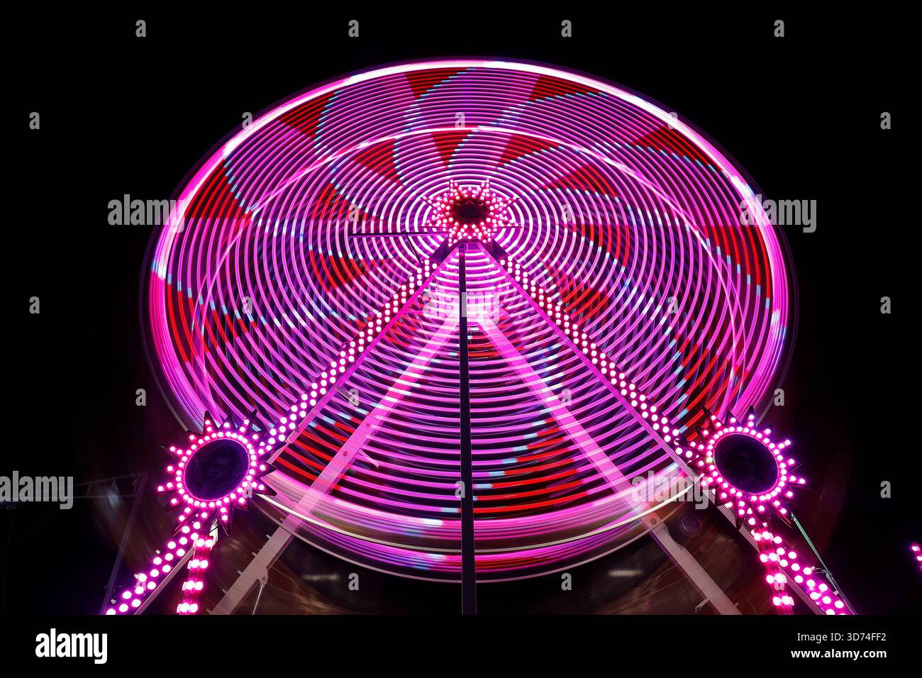 Lunga esposizione di una ruota panoramica illuminata di notte durante l'evento dell'aurora boreale al Temple Newsam di Leeds, West Yorkshire, Regno Unito Foto Stock