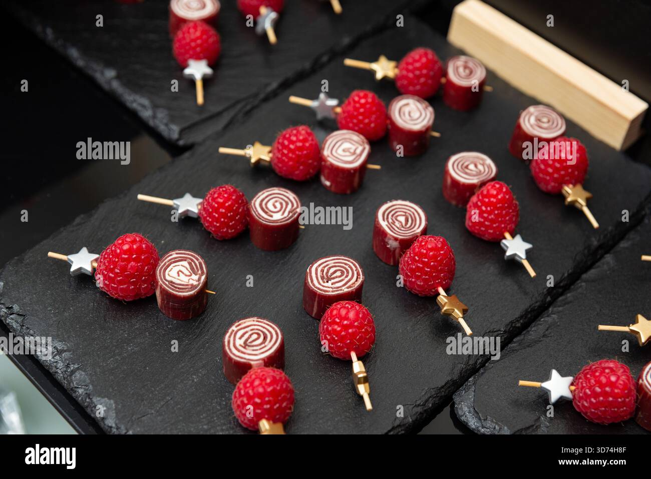 Eleganti prelibatezze di lamponi e cioccolato presentate su piatti di ardesia. perfetti per le feste, questi accattivanti dessert combinano sapori ricchi con un Foto Stock
