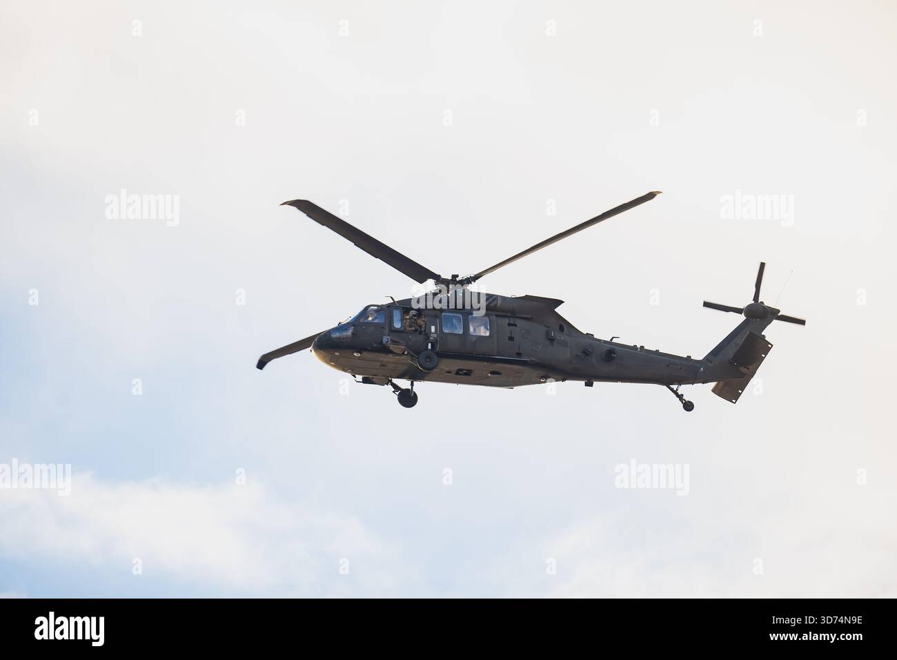 Elicottero delle forze armate con fusoliera mimetica, sistema a doppio rotore e struttura tattica della cellula catturati durante il movimento aereo sotto il cielo chiaro Foto Stock