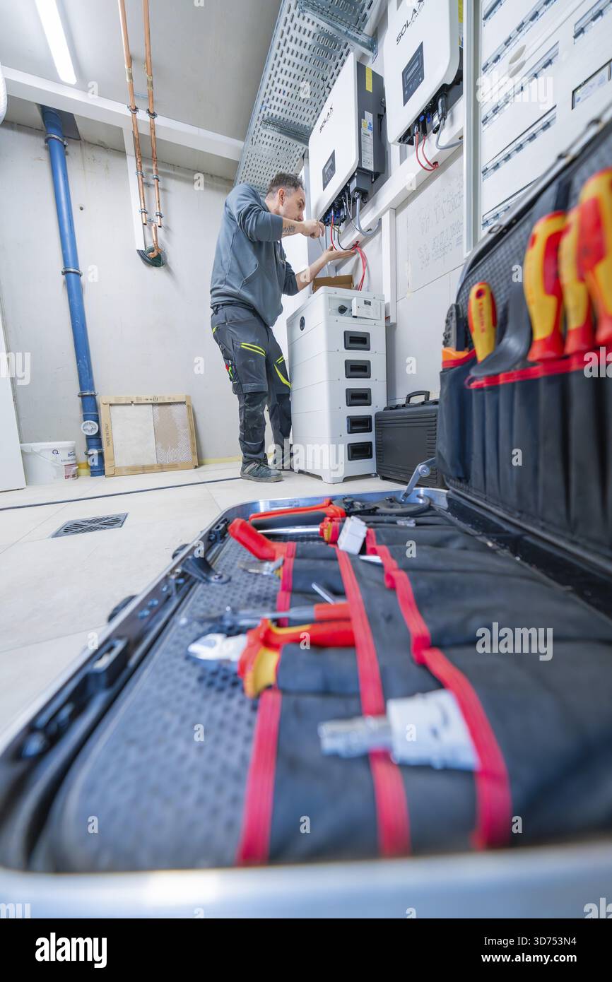 Elettricista che lavora in una sala tecnica con cassetta degli attrezzi in primo piano Foto Stock