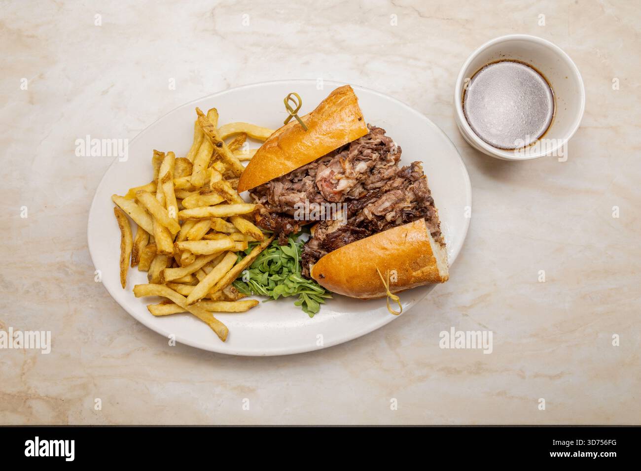 La migliore immersione a costolette. Manzo grattugiato tenero, accatastato su un panino tostato, servito con un lato di patatine fritte croccanti e ricco au jus. Il pranzo è servito. Foto Stock