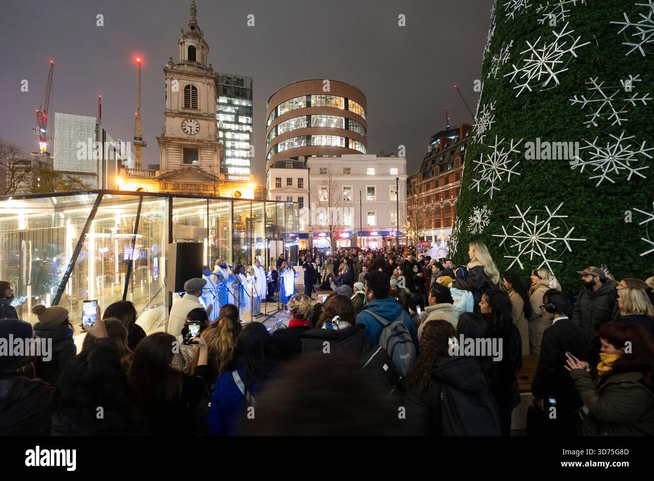 Un coro canta al One Bishopsgate Plaza di Londra, durante un festoso evento di illuminazione degli alberi di Natale. Foto Stock