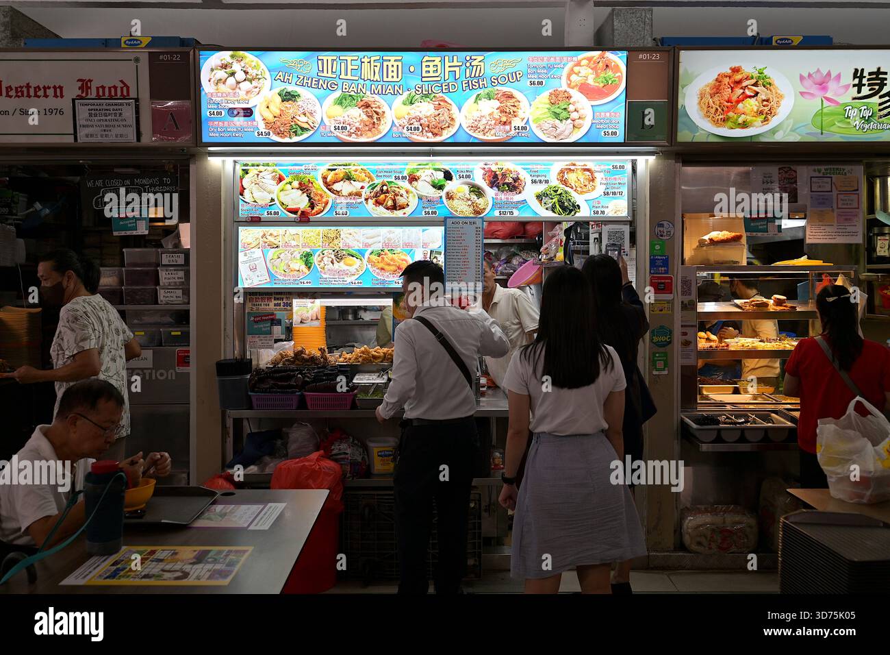 Fai la fila in una bancarella di cibo che vende zuppa di pesce e spaghetti banmiani al Marine Parade Hawker Centre, una popolare area ristoro all'aperto di Singapore Foto Stock