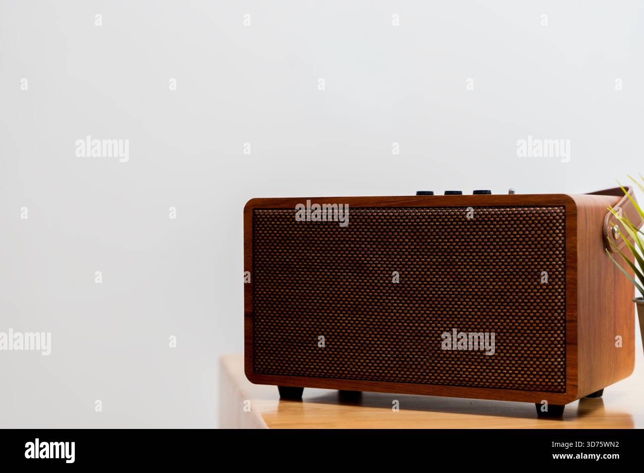 Altoparlante in legno retrò posizionato su un tavolo minimalista, che mette in risalto la texture calda e la funzionalità moderna. Ideale per i temi dell'arredamento della casa, della tecnologia audio, Foto Stock