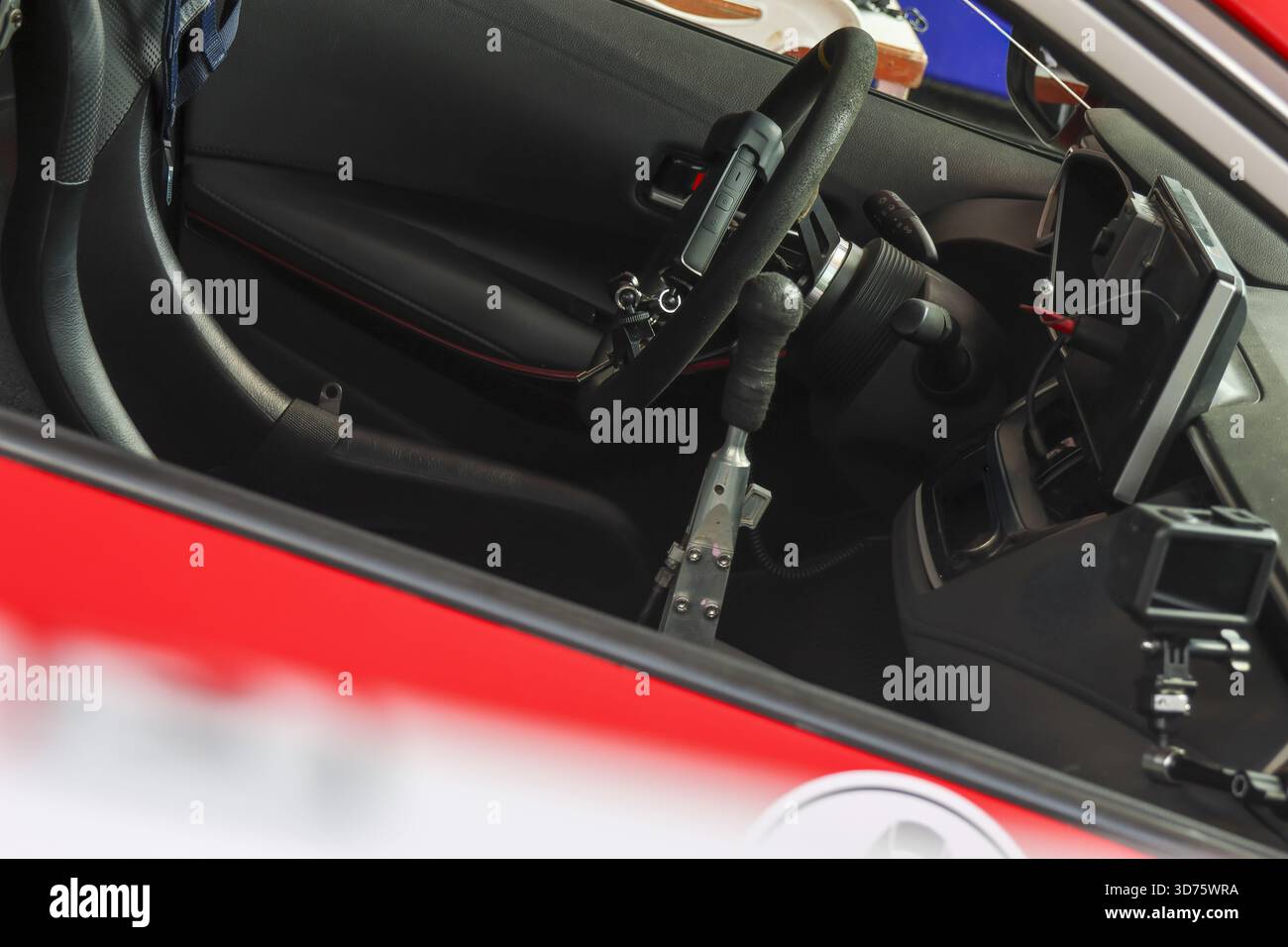 Primo piano degli interni delle moderne auto sportive rosse, con eleganti sedili, volante e cruscotto in pelle nera. il design della cabina di pilotaggio evoca una sensazione di potenza Foto Stock