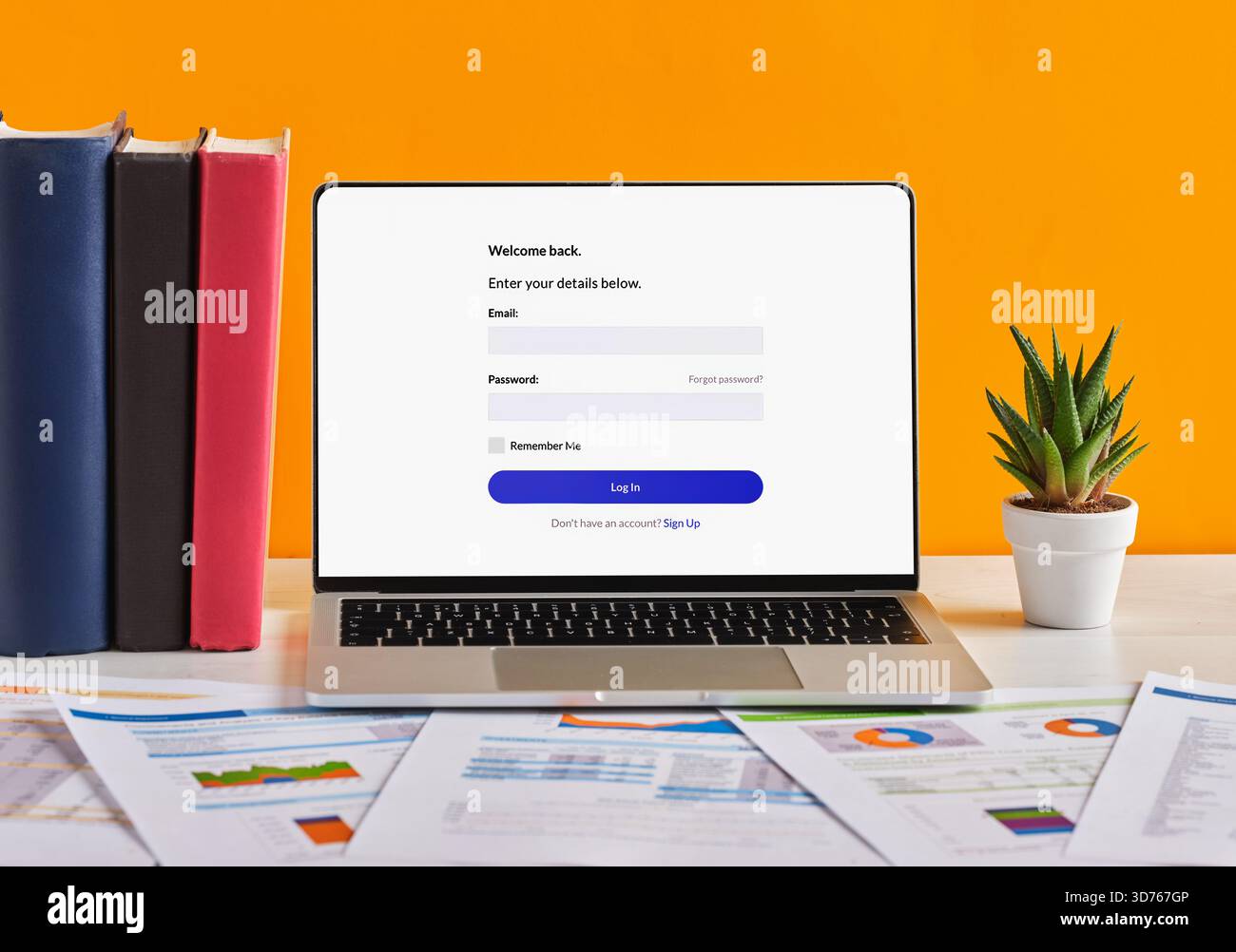 Apri il laptop con la schermata di accesso sulla scrivania con documenti, libri e impianti sullo sfondo arancione Foto Stock