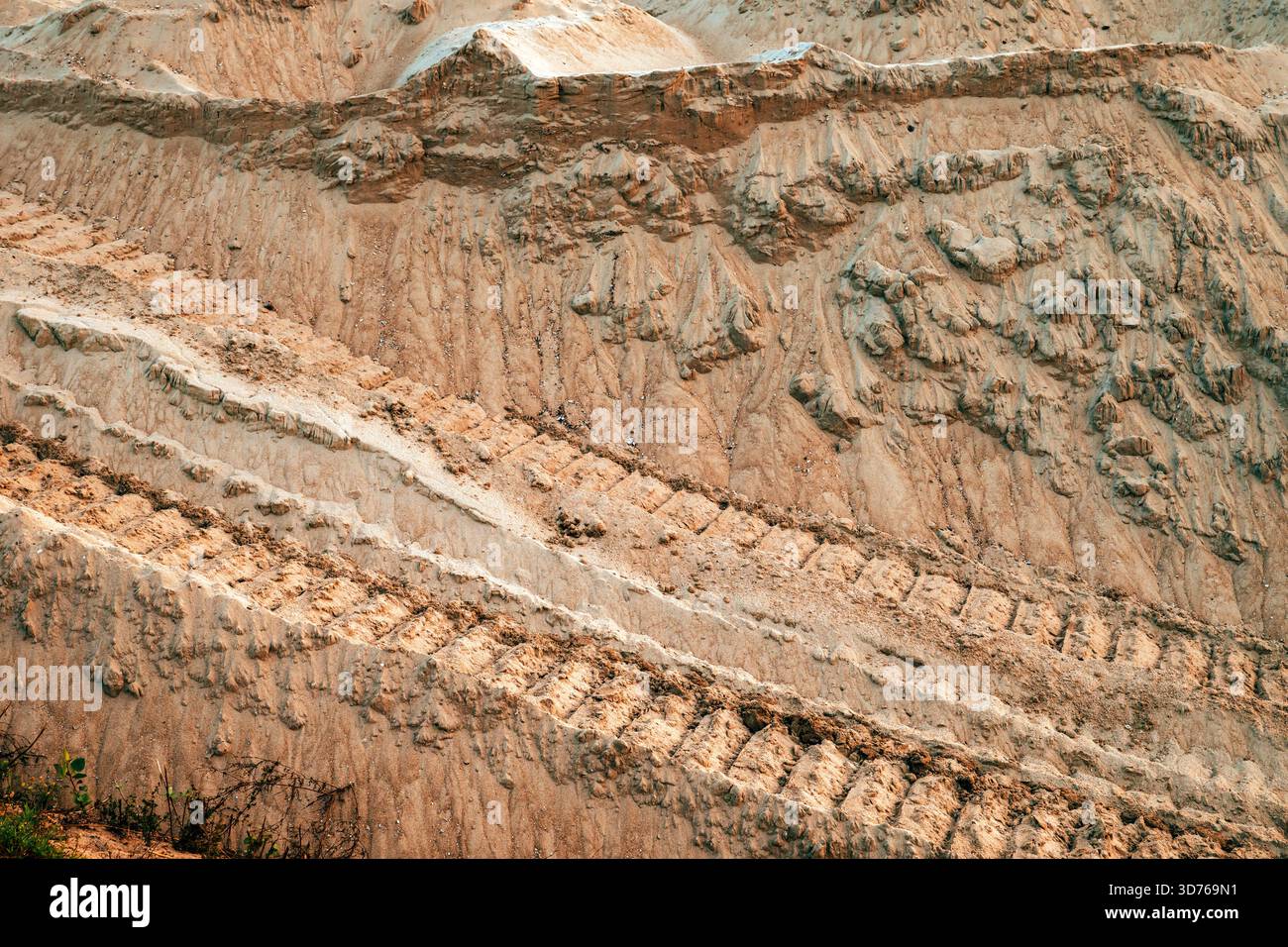 Vista dettagliata della collina sabbiosa del cantiere che mostra i marchi di macchinari pesanti e le consistenze naturali dell'erosione. Messa a fuoco selettiva. Foto Stock