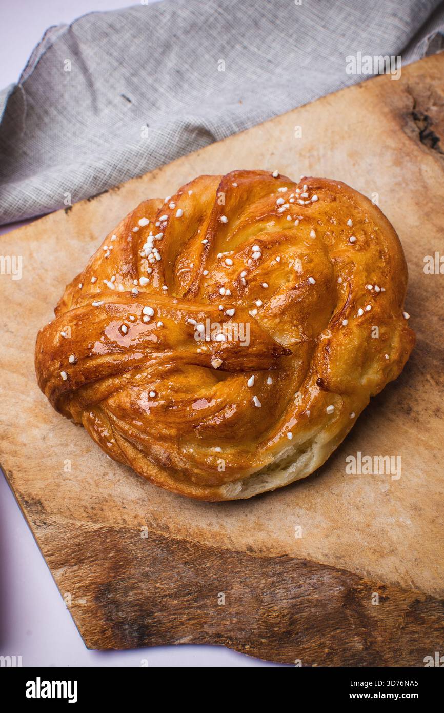 Panino dolce appena sfornato con zucchero perlato su tavola di legno rustico. Stile scandinavo. Foto Stock