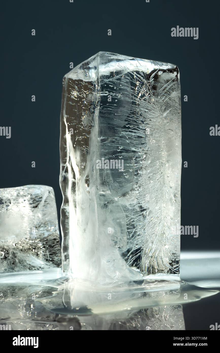 Blocco trasparente di ghiaccio retroilluminato su sfondo blu scuro Foto Stock