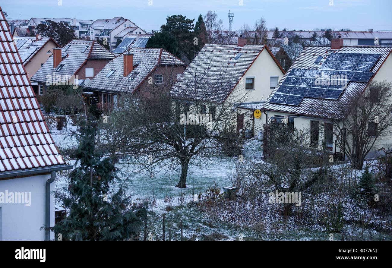 Lipsia, Germania. 24 novembre 2025. Diversi edifici residenziali in una proprietà residenziale sono coperti di neve e un grande impianto fotovoltaico può essere visto su uno dei tetti. Crediti: Jan Woitas/dpa/Alamy Live News Foto Stock