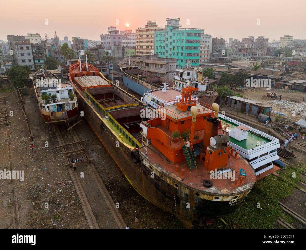 Veduta aerea delle navi attraccate in un vasto paesaggio urbano, il sole tramonta proiettando un caldo bagliore sulla scena, Dacca, Divisione di Dacca, Bangladesh. Foto Stock