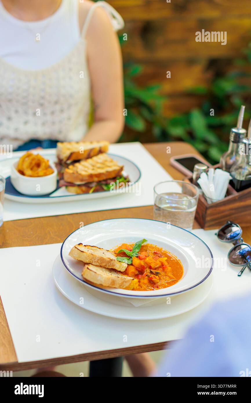 Tavolo del ristorante all'aperto con zuppa di pomodoro e sandwich alla griglia Foto Stock
