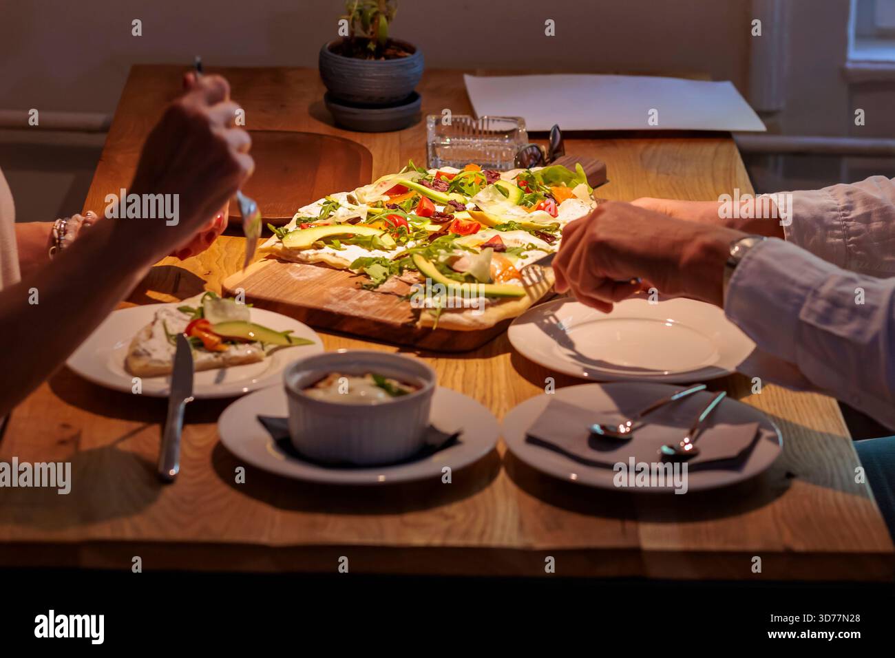 Coppia che si gusta una focaccia appena sfornata condita con verdure in un ambiente accogliente per cena Foto Stock