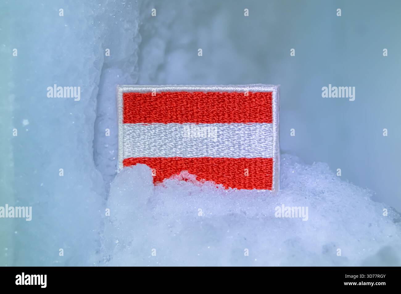 Bandiera austriaca sulla neve glaciale, che evoca lo sci invernale nelle Alpi tirolesi, viaggi alpini, temi di spedizione e consapevolezza del clima. Foto Stock