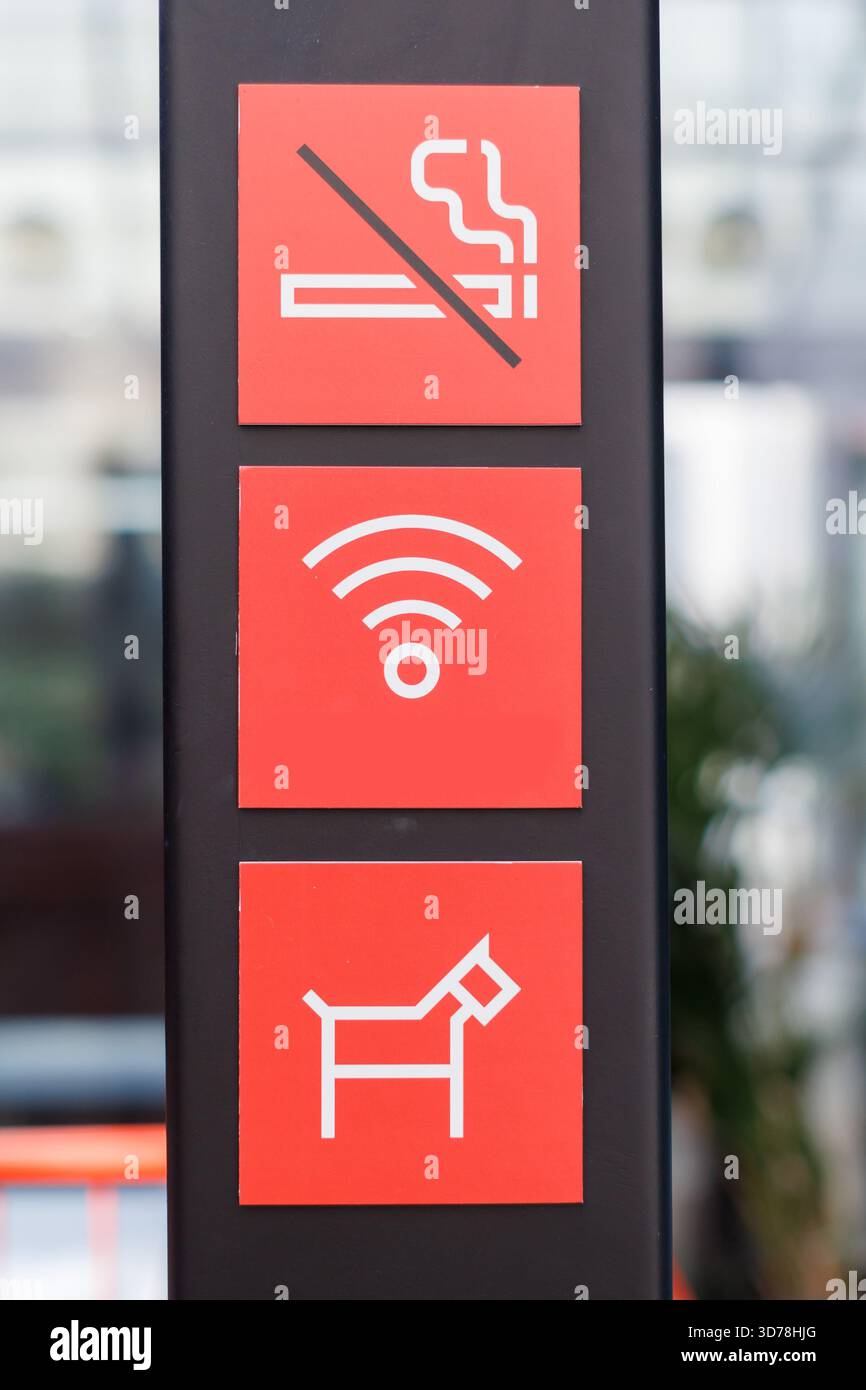 Cartello che indica che non è consentito fumare, che è disponibile l'accesso Wi-Fi a Internet e che sono ammessi i cani in un ambiente urbano Foto Stock