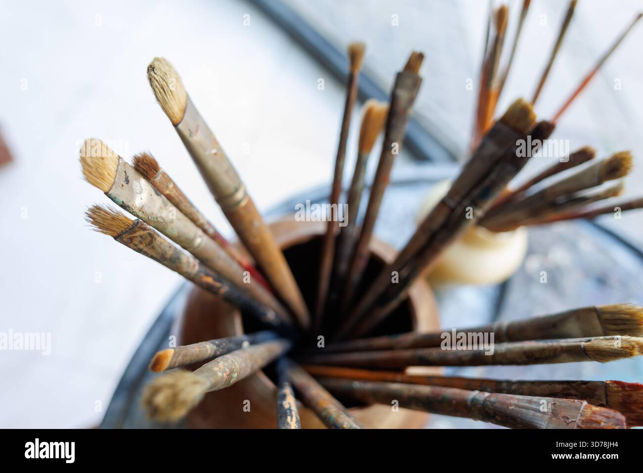La collezione di pennelli dell'artista è esposta in un supporto in legno su un tavolo colorato in uno spazio di lavoro creativo Foto Stock