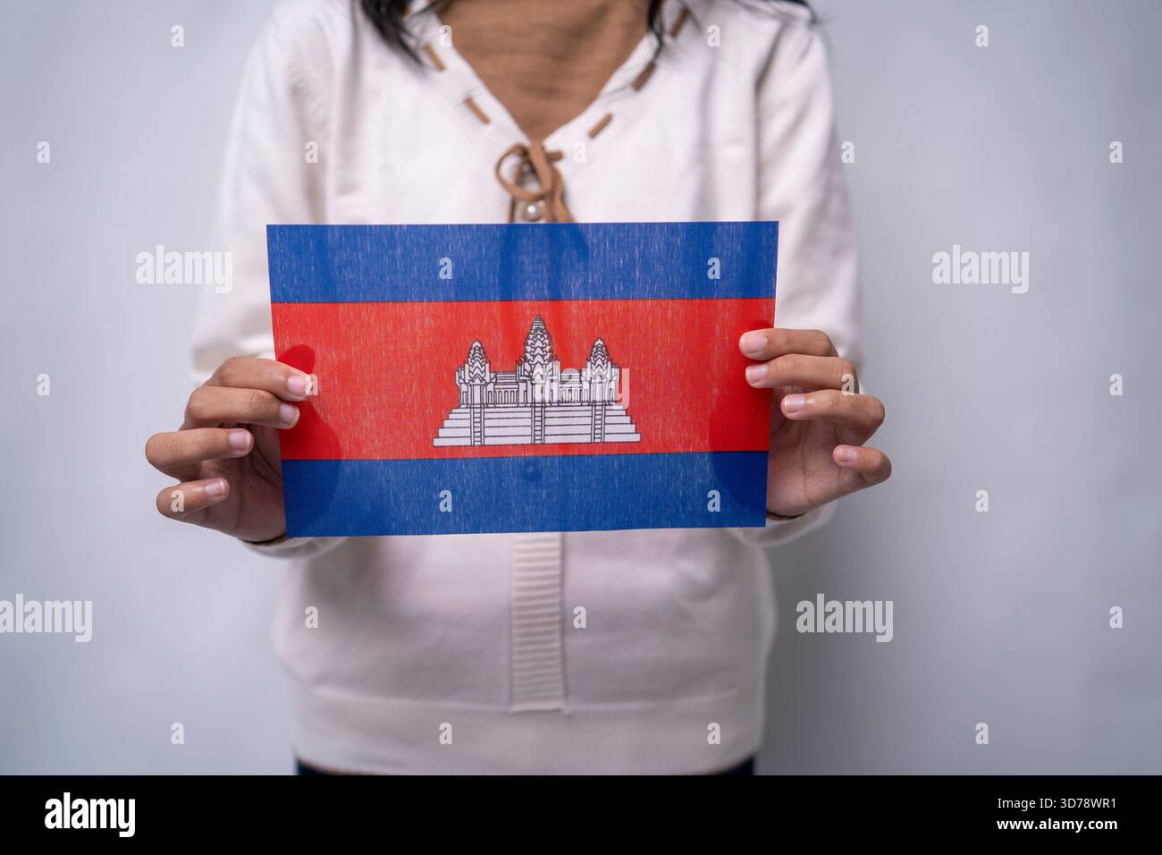 Persona che detiene la bandiera nazionale cambogiana in un contesto neutrale Foto Stock
