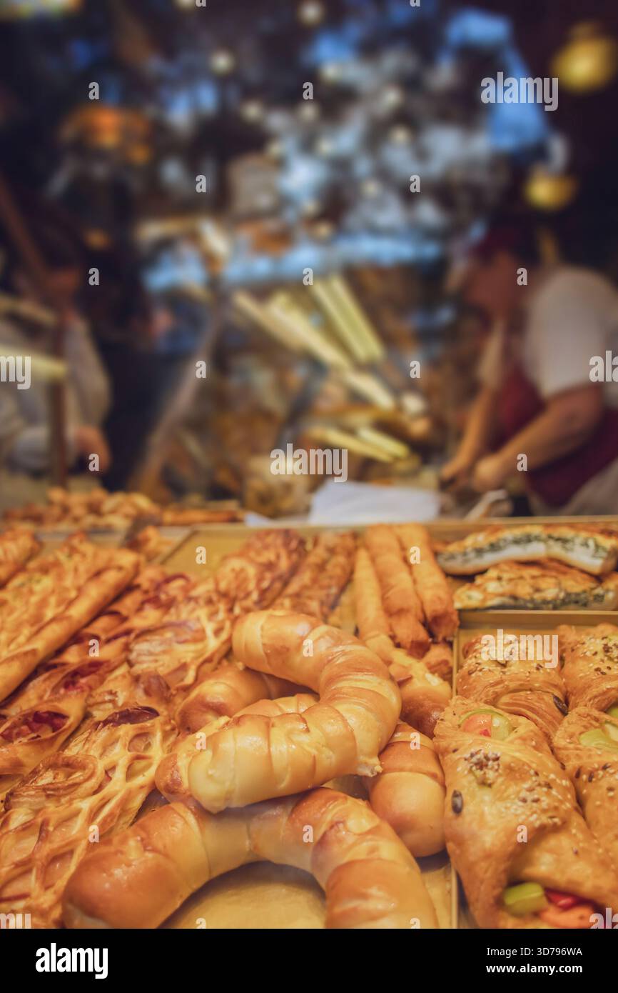 Pasticcini e pane appena sfornati esposti in una vivace panetteria in un vivace mercato durante le ore mattutine Foto Stock