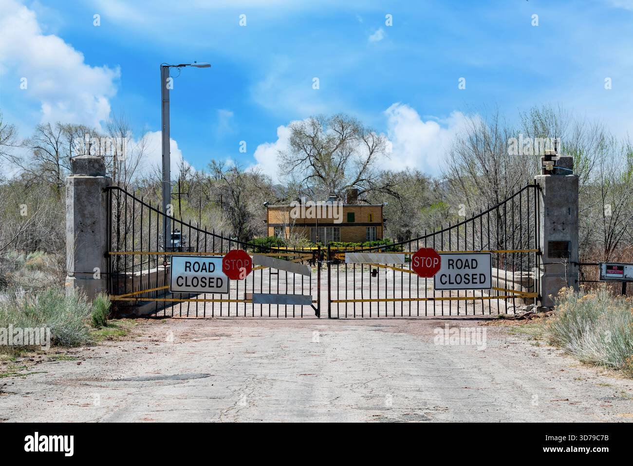 Un cancello chiuso sorgeva lungo una strada desertica presso l'abbandonato Fort Wingate, New Mexico, tranquillo sotto un cielo limpido. Foto Stock