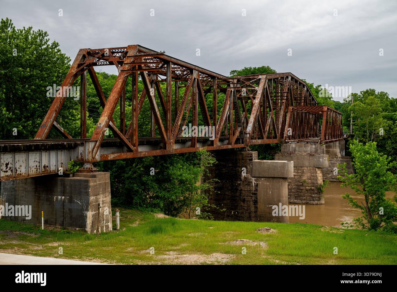 Questa è una cupa vista estiva di una strada abbandonata attraverso il ponte a capriata e di un ponte ferroviario adiacente sul fiume Kentucky. Foto Stock