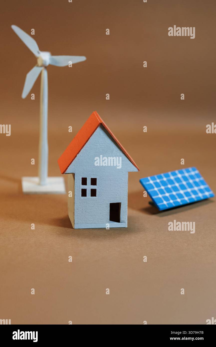 Modello che rappresenta l'energia rinnovabile con una casa, una turbina eolica e un pannello solare su sfondo neutro Foto Stock